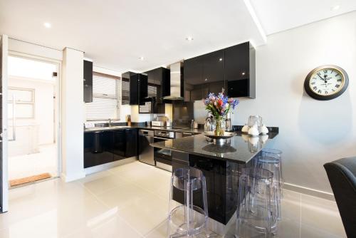 a kitchen with black cabinets and a clock on the wall at Lux Andringa Walk Apartments in Stellenbosch