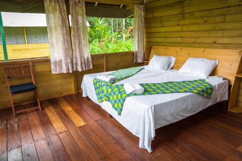 a bed in a wooden room with a window at Lirio Lodge in Barra de Pacuare