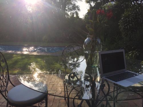 a laptop computer sitting on a glass table with chairs at Rukka Lodge in Tumbaco