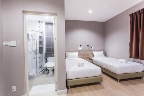 Duas camas num quarto com um chuveiro e uma casa de banho em Morino Hotel Si Racha em Si Racha