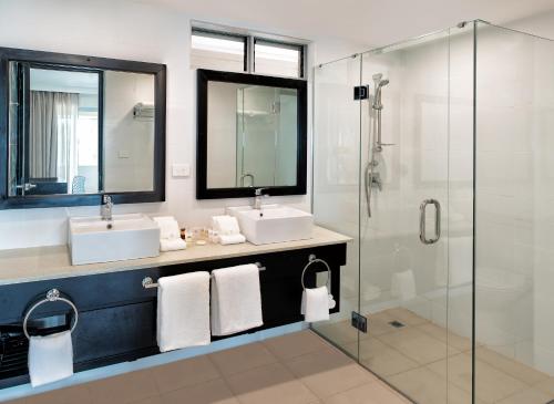 a bathroom with two sinks and a glass shower at Tanoa International Dateline Hotel in Nuku‘alofa