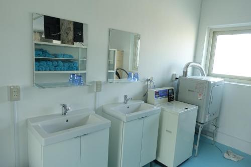 a white bathroom with two sinks and a washing machine at Hostel NABLA in Niijimamura