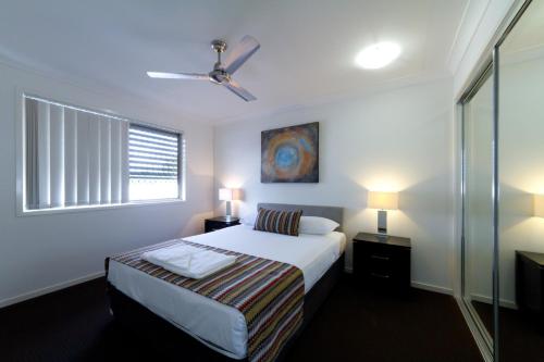a bedroom with a bed and two lamps and a window at Rockhampton Serviced Apartments in Rockhampton