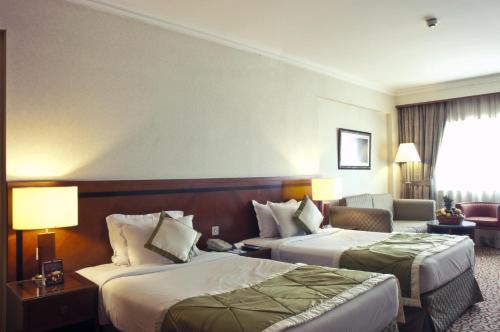 a hotel room with two beds and a couch at Ramee Royal Hotel in Dubai