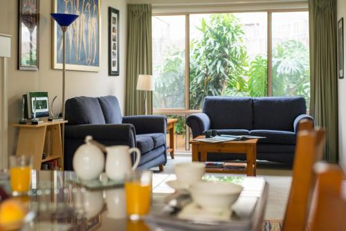 a living room with blue couches and a table at Bellevue Bed & Breakfast in McLaren Vale
