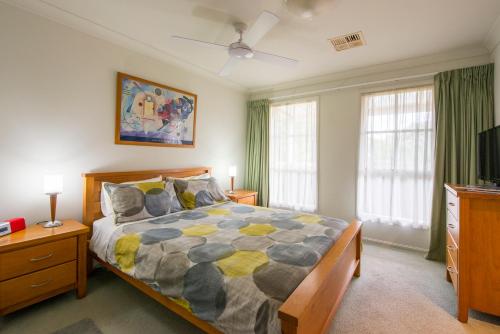 a bedroom with a bed and a tv and windows at Bellevue Bed & Breakfast in McLaren Vale