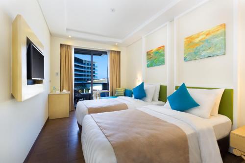 a hotel room with two beds and a television at Savoy Hotel Boracay Newcoast in Boracay