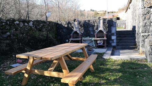 a wooden picnic table with a grill in a yard at Viola Nel Parco in SantʼAlfio