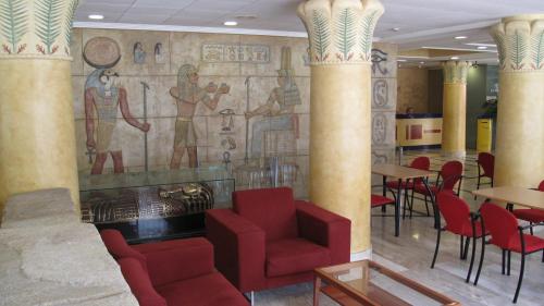 a restaurant with red chairs and a mosaic wall at Cleopatra Spa Hotel in Lloret de Mar