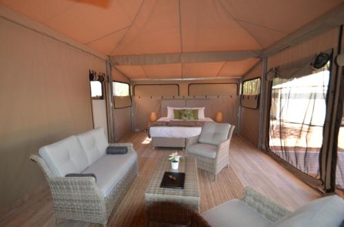 a bedroom in a tent with a bed and chairs at Coalmine Beach Holiday Park in Walpole