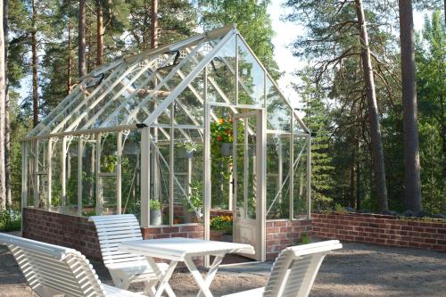 a greenhouse with a table and chairs in front of it at Hotelli Punkaharju in Punkaharju