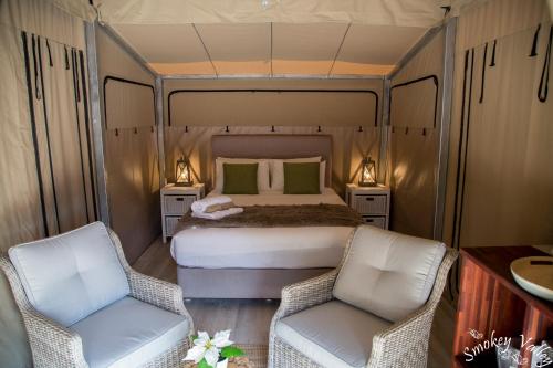 a bedroom with a bed and two chairs at Coalmine Beach Holiday Park in Walpole