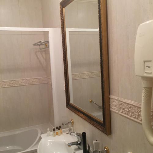 un bagno con uno specchio, un lavandino e una vasca di Alex Apartment Sofia a Sofia