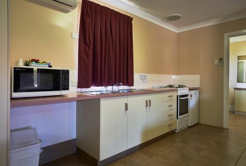 a kitchen with a counter with a microwave and a sink at Jefferys Motel in Toowoomba