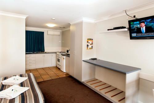 a room with a kitchen with a tv on the wall at Jefferys Motel in Toowoomba