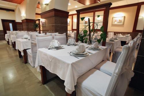 Un comedor con mesas blancas y sillas blancas. en Hotel Narona, en Metković
