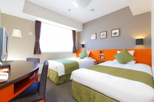 a hotel room with two beds and a desk at HOTEL MYSTAYS Kyoto Shijo in Kyoto