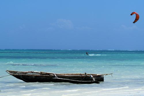 a boat on the beach with a kite in the water at Pinewood Beach Resort and Spa in Diani Beach