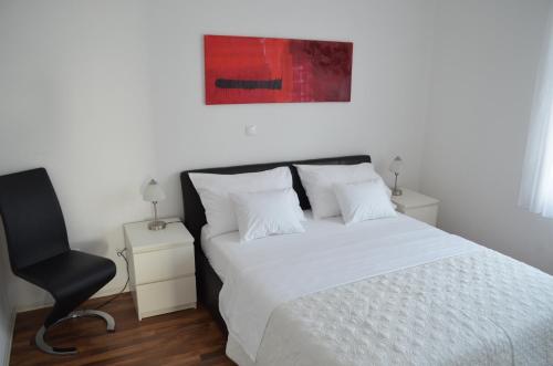 a bedroom with a white bed and a black chair at Luxury Apartments Zana in Zadar