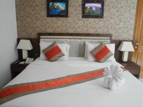 a bedroom with a large white bed with two lamps at Hotel on The Rock in Kupang