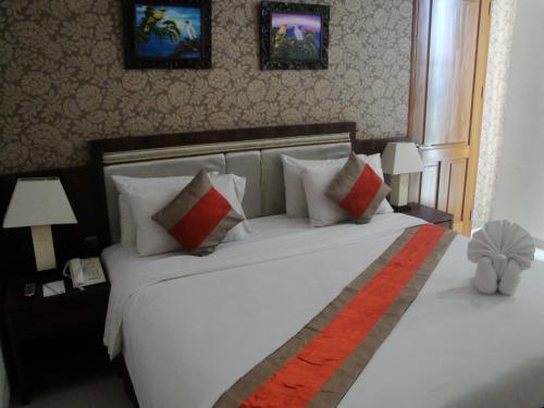 a bedroom with a large white bed and two lamps at Hotel on The Rock in Kupang