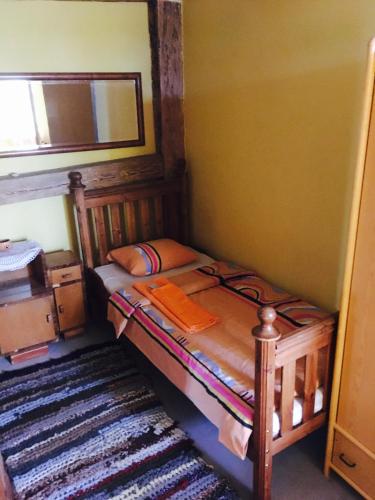 a small bedroom with a bed and a mirror at Baltā māja in Pilsrundāle