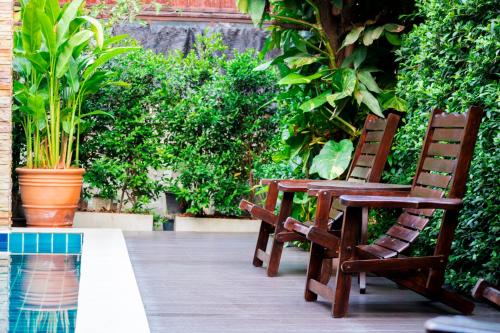 two wooden chairs sitting on a patio with plants at i Lanna House in Chiang Mai