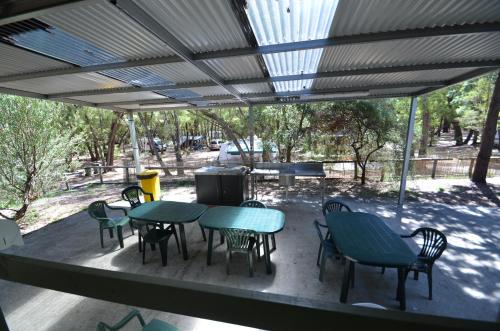 a patio with tables and chairs and a grill at Coalmine Beach Holiday Park in Walpole