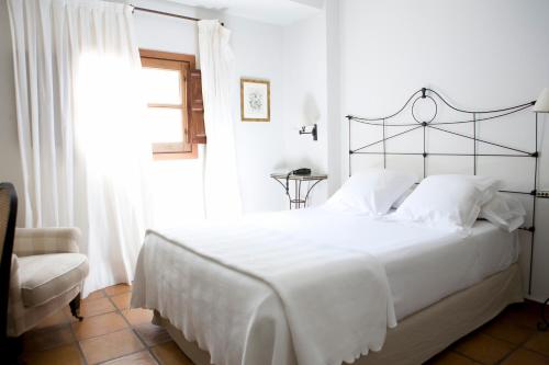 a white bedroom with a large bed and a window at Palacio De Los Navas in Granada