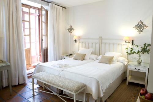 a white bedroom with a large bed and a window at Palacio De Los Navas in Granada