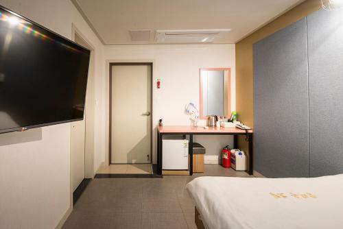 a hotel room with a bed and a desk and a television at Champion Hotel in Jeju