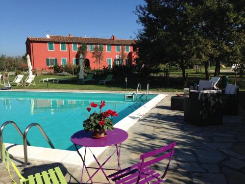 a table with flowers on it next to a pool at Country House Podere Le Rane Felici in Fauglia