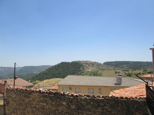 a building with a stone wall and mountains in the background at serranía del tajo in Peñalén