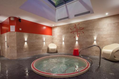 a bathroom with a hot tub with a faucet at Hôtel & Spa Le Bouclier D'or in Strasbourg