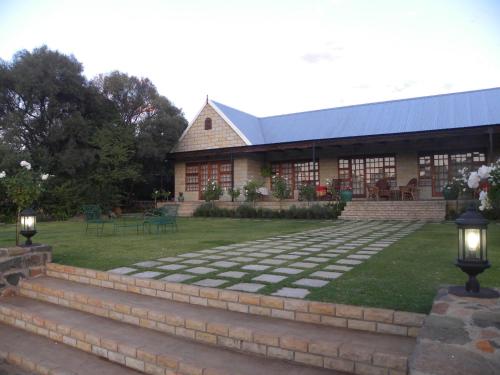 a building with a stone path in front of a yard at Olive Hill Country Lodge in Bloemfontein