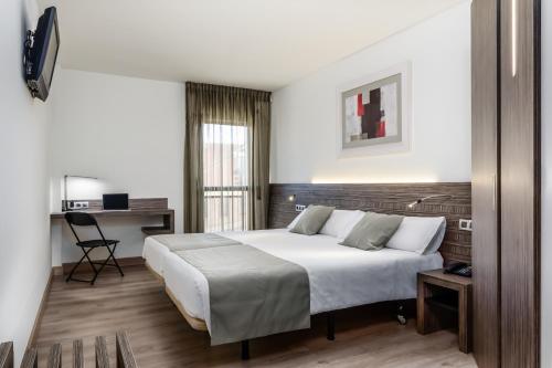 a bedroom with a large white bed and a desk at Hotel HC*** Mollet Barcelona in Mollet del Vallès