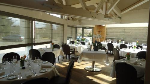 un restaurante con mesas y sillas con manteles blancos en Le Moulin de la Walk en Wissembourg