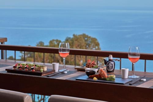 a table with two plates of food and glasses of wine at Grecian Park in Protaras