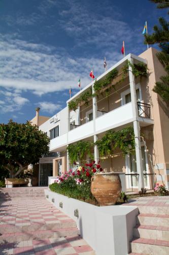 a white building with flowers in front of it at Hotel Peli in Kissamos