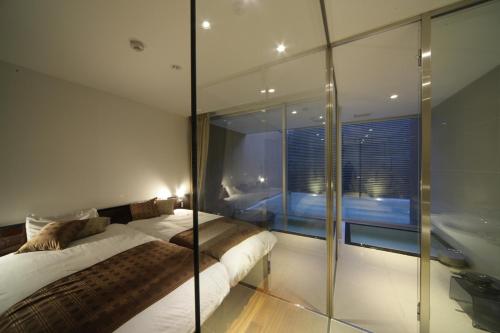a bedroom with two beds and a glass wall at Four Seasons Yuzawa Quattro in Yuzawa