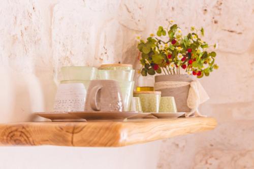 a shelf with dishes and a vase with flowers on it at Materiis in Noci