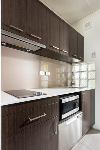 a kitchen with wooden cabinets and a stove top oven at Pier 21 Riverside Apartment Hotel in Fremantle