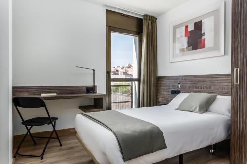 a bedroom with a bed and a chair and a window at Hotel HC*** Mollet Barcelona in Mollet del Vallès