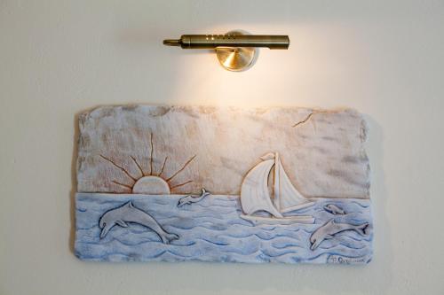 a painting of the ocean with a sailboat on a wall at Mata's Apartments in Tinos Town