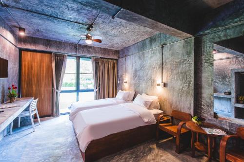 a bedroom with a large bed and a desk and a table at Stucco Loft Residency in Chiang Mai