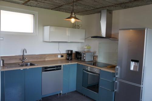 a kitchen with blue cabinets and a sink at Gîte l'Atelier in Lecelles