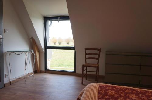 a bedroom with a bed and a chair and a window at Gîte l'Atelier in Lecelles