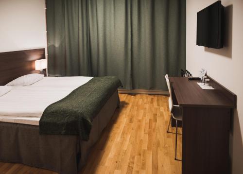a bedroom with a bed and a desk with a television at Stay Xtra Hotel Kista in Stockholm