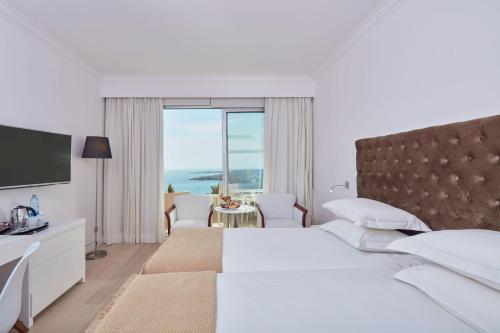 a white bedroom with a large bed and a large window at Grecian Park in Protaras
