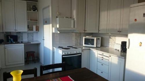 a kitchen with white cabinets and a stove and a table at Kairalan Kievari in Salla